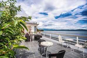 A terrace with outdoor seating, a view of the water, and a building with traditional architecture. - Dali Huayue Fanxing Sea View Inn (Dali City)