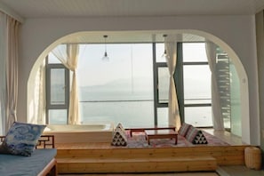 Una habitación con un amplio ventanal de arco, asientos de madera y vista al mar.
