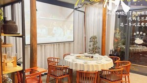 A dining area with round tables and orange chairs, a projector screen, and a decorative plant. - Lishui Zhugeshijia homestay (Lishui)