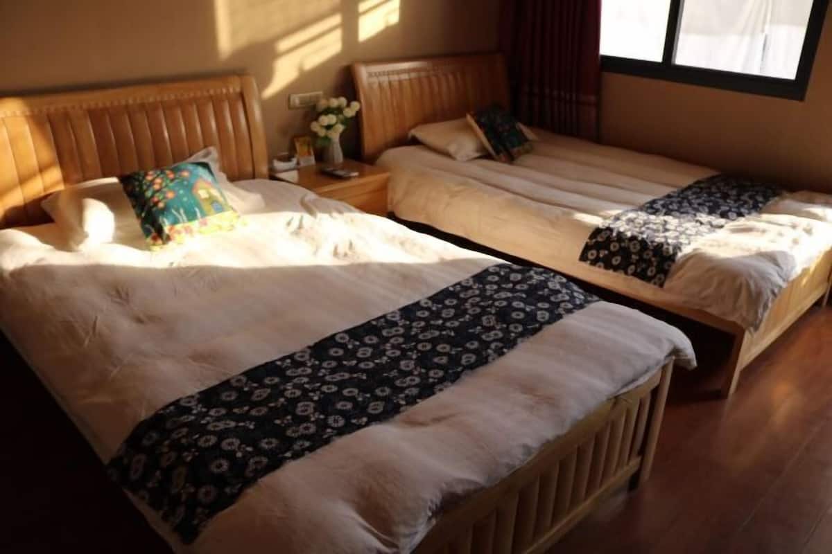 A room with two beds, each with a headboard, a bedside table, and a lamp.