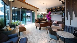 Un salon moderne doté d’une table de billard, de sièges confortables et offrant une vue dégagée grâce à de grandes fenêtres.