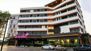 Un hôtel à plusieurs étages doté d’une architecture moderne, avec une enseigne au néon bien visible au rez-de-chaussée.