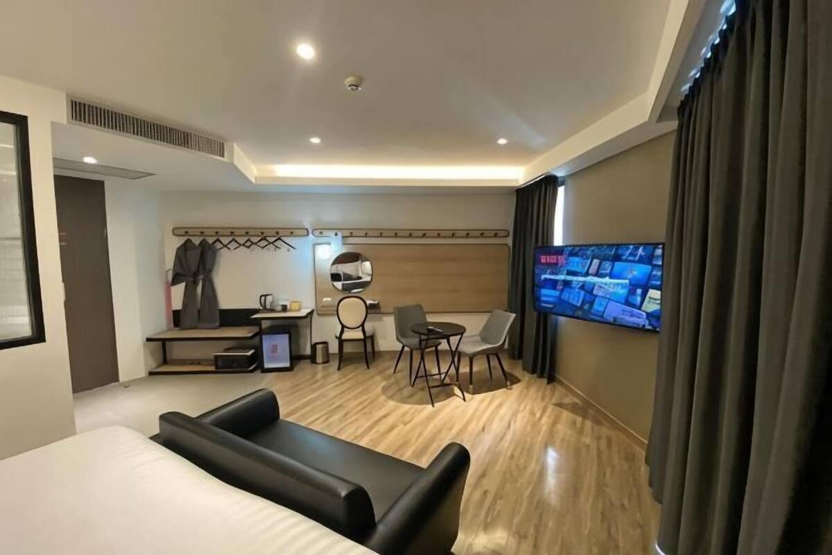 Une chambre d’hôtel comprenant un lit, un bureau avec une chaise, une télévision et un coin salon.