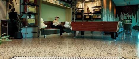 Un vestíbulo de hotel con mesa de billar, zona de estar y una alfombra decorativa que dice 'SCARLETT'.
