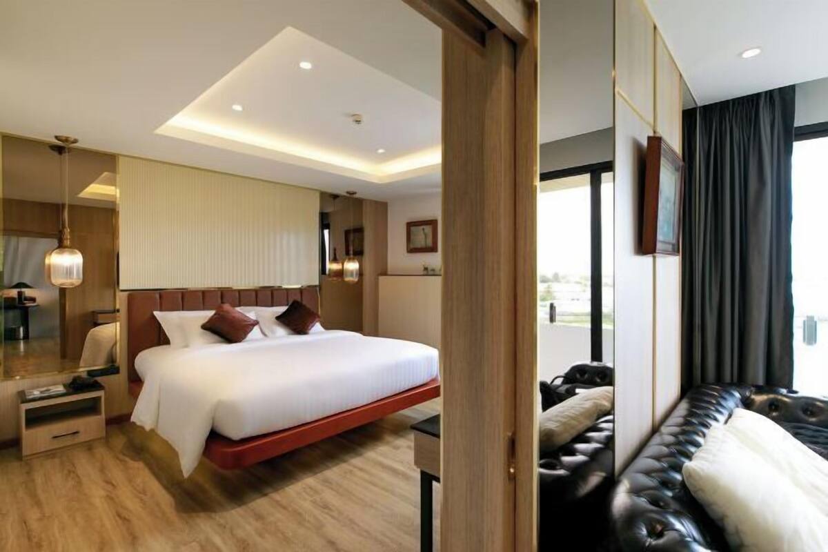 Une chambre d’hôtel avec un lit, une table de chevet et un grand miroir.