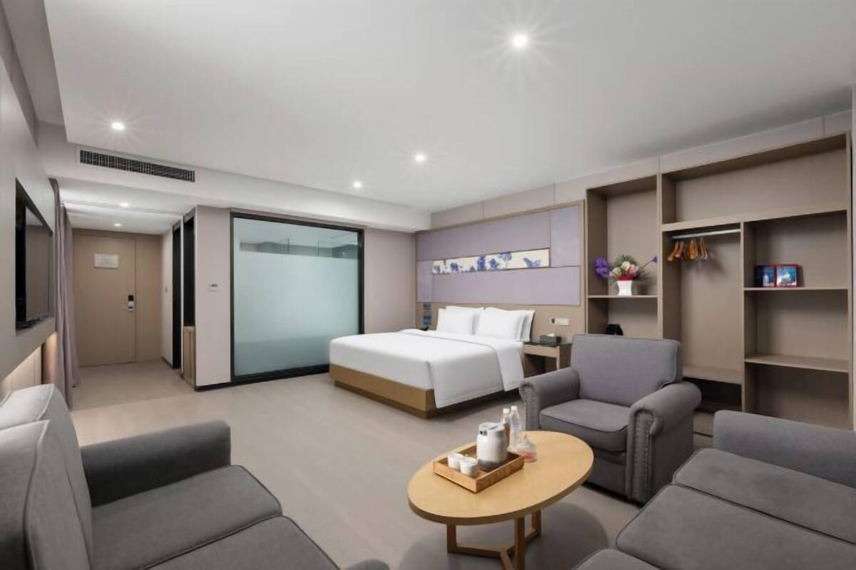 Ein modernes Hotelzimmer mit einem Bett, einer Sitzecke mit Tisch und integrierten Regalen.