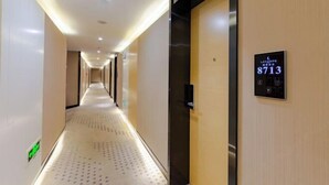 A hotel corridor with a long, narrow layout, a digital room number display, and a modern elevator. - Lavande Hotel Wuhan Wujiashan 5th Ring Sports Center (Wuhan)