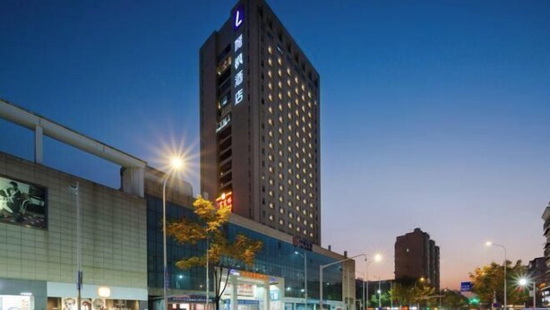 A high-rise hotel with a prominent 'L' logo on the top, multiple floors with evenly spaced windows, and a modern glass facade. - Lavande Hotel Wuhan Wujiashan 5th Ring Sports Center (Wuhan)