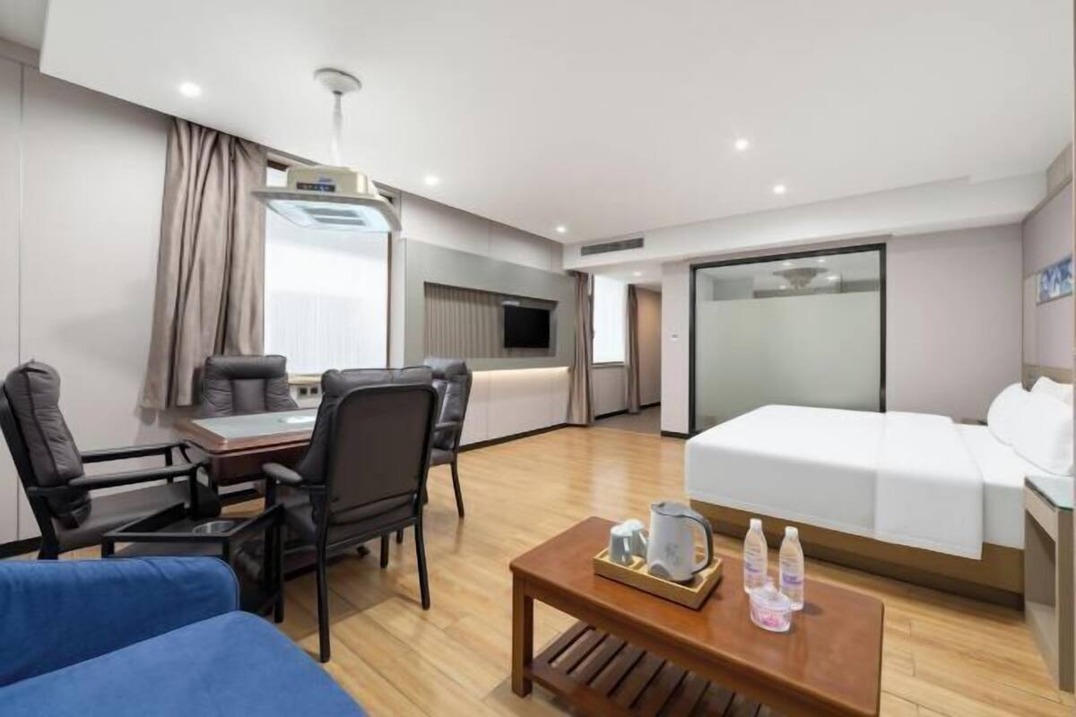 Ein Hotelzimmer mit einem Bett, einem Schreibtisch mit Stühlen, einem Couchtisch und einem Fernseher.