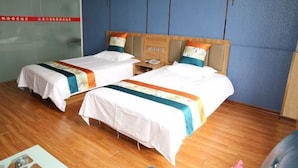 Habitación de hotel con dos camas, piso de madera y una pared azul decorativa.