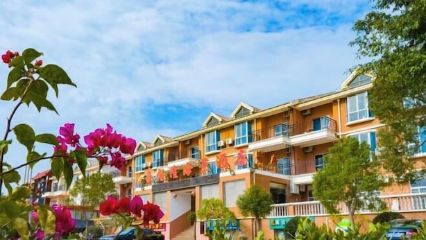 Un hotel de varios pisos con balcones, una entrada cubierta y un área de estacionamiento.