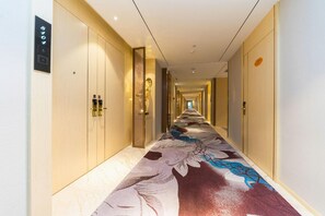 Un pasillo de hotel con alfombra estampada, puertas de madera y suelo de color claro.