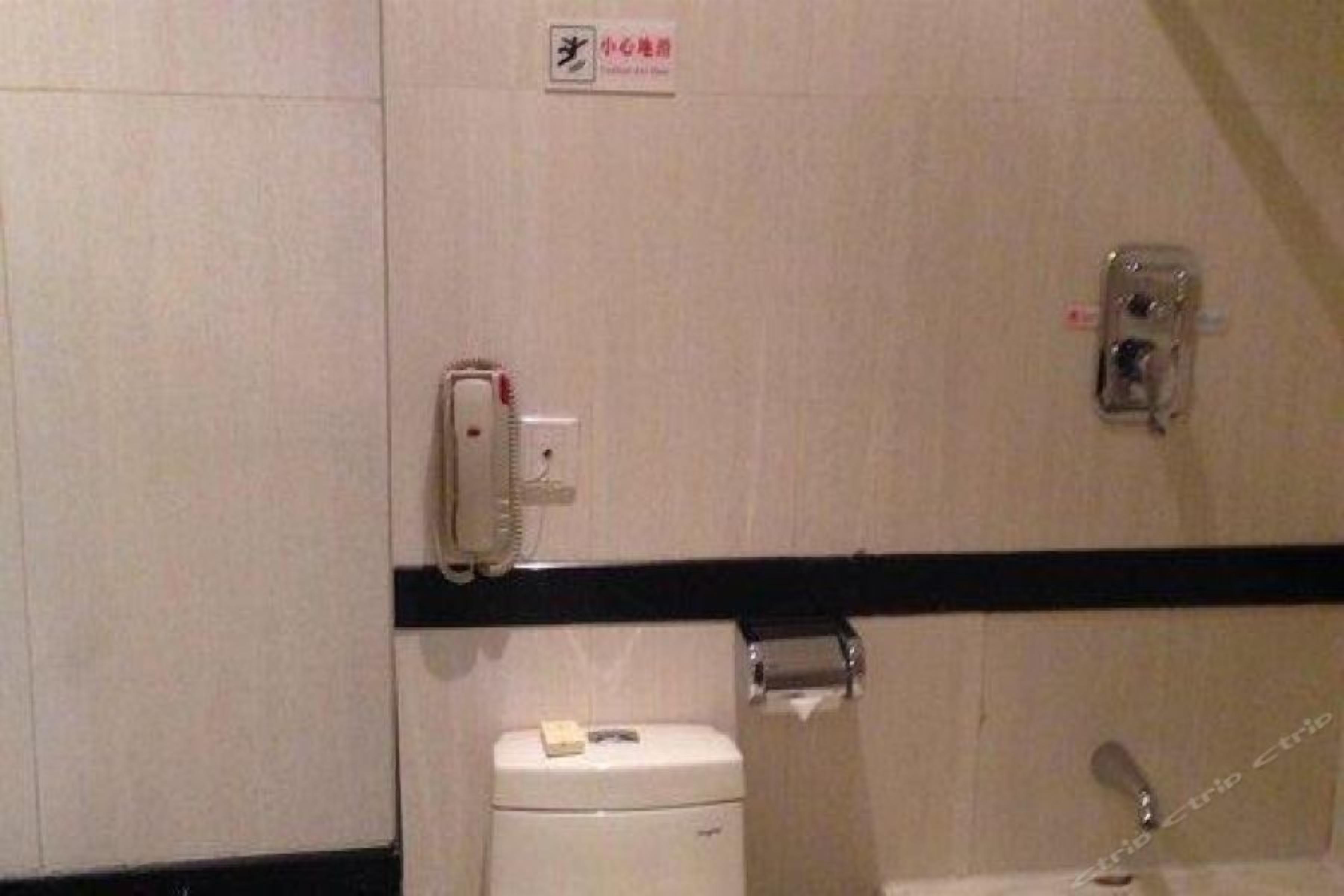 A bathroom with a toilet, a paper towel dispenser, and a hand dryer.