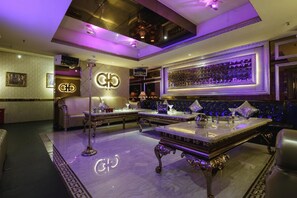 Un área de bar lujosa con suelo de mármol, muebles ornamentados y un letrero de neón.