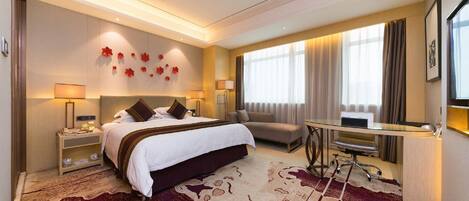 A hotel room with a large bed, a desk, a sofa, and a view of the outdoors.