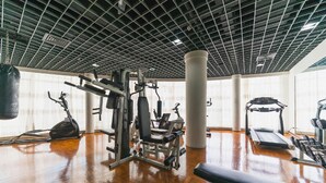 A gym with various exercise equipment, a punching bag, and a treadmill. - Rich Forex Hotel (Foshan)