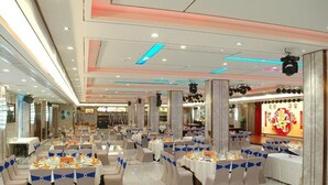 A banquet hall with multiple round tables, each set with white tablecloths and blue sashes. - Rich Forex Hotel (Foshan)