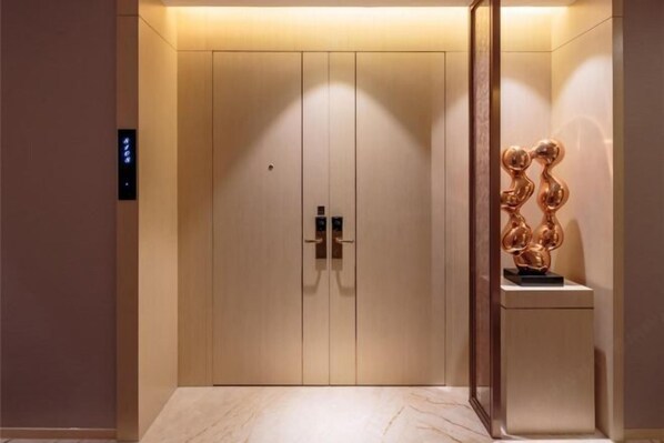 Elevador moderno com design minimalista, apresenta acabamento em madeira clara e painel de controle digital à esquerda.