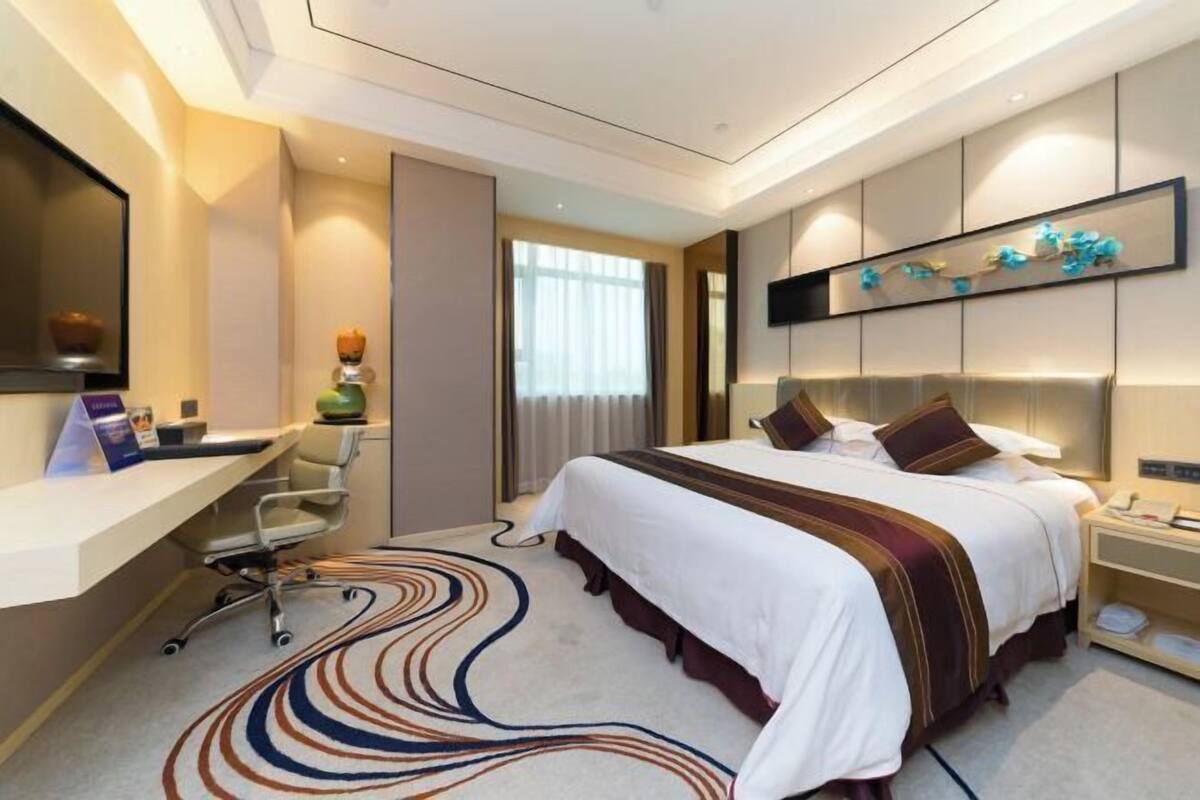 A modern hotel room with a large bed, a desk, and a chair.