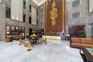 A spacious lobby with marble flooring, a reception desk, seating areas, and a large decorative wall. - Rich Forex Hotel (Foshan)