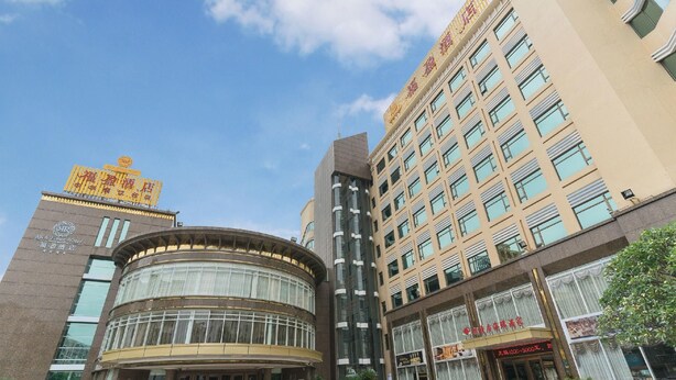 A hotel with a prominent sign, a curved facade, and a tall building with many windows. - Rich Forex Hotel (Foshan)