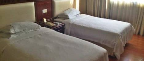 A hotel room with two beds, a nightstand, and a lamp.