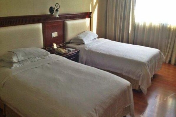Une chambre d’hôtel avec deux lits, une table de chevet et une lampe.
