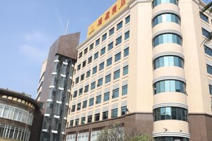 A multi-story hotel with a modern facade, featuring a prominent yellow sign with red lettering. - Rich Forex Hotel (Foshan)