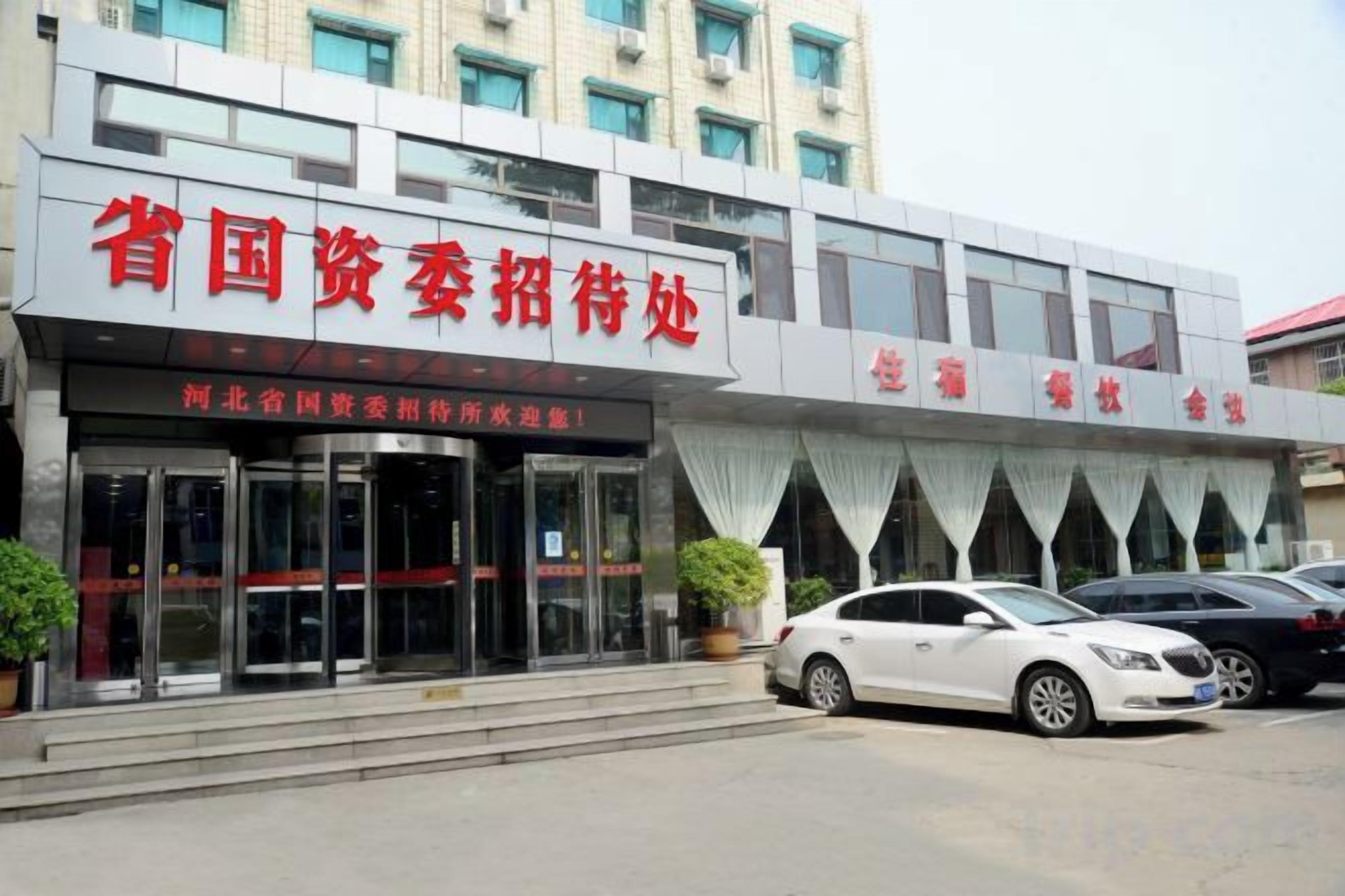 Un bâtiment sur lequel on peut lire l’inscription « Bureau de recrutement de la province, à la recherche de talents », et un parking avec des voitures.