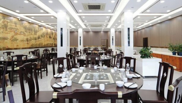 A dining area with round tables, chairs, and a mural on the wall. - Hebei Provincial State-owned Assets Supervision and Administration Commission (Shijiazhuang)