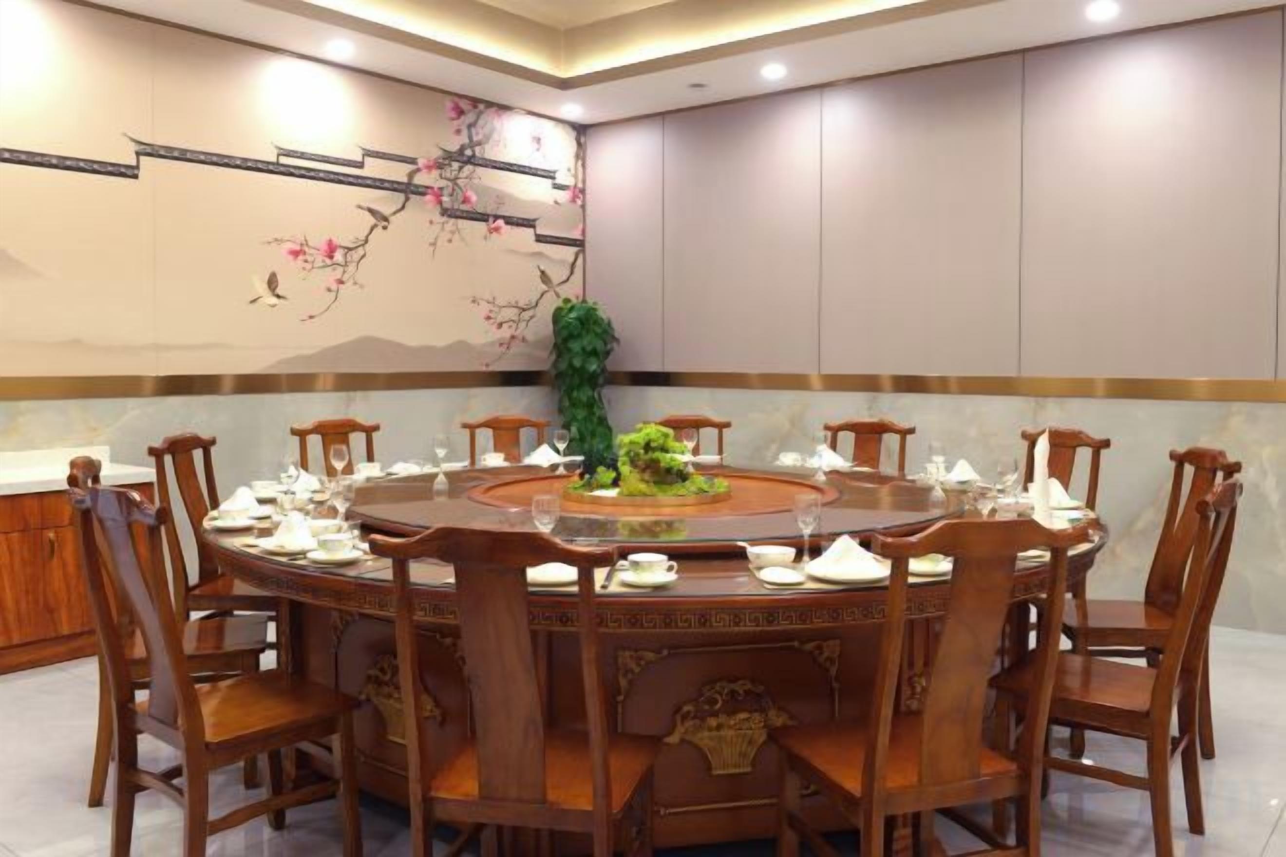 Una mesa de comedor redonda con sillas, una planta decorativa en el centro y una pared con un mural floral.