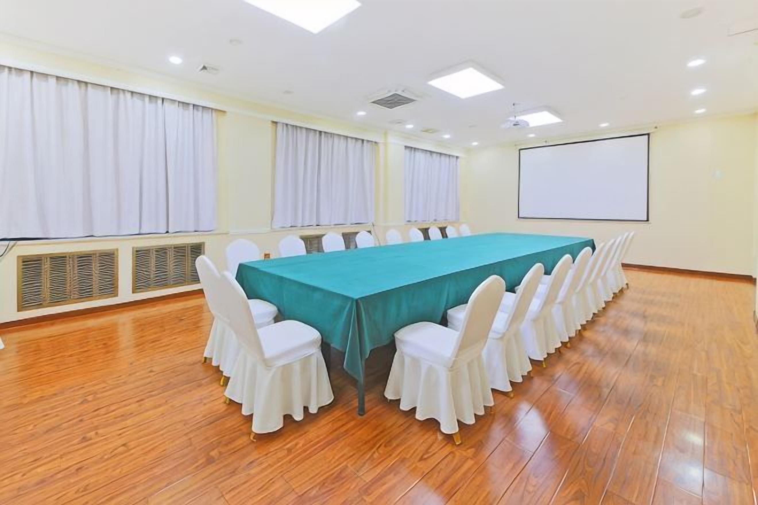 A conference room with a long table, white chairs, a projector screen, and a whiteboard.