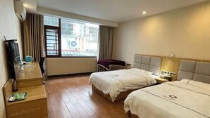 Une chambre d’hôtel avec deux lits, un bureau, une chaise, une télévision et une fenêtre avec des rideaux.