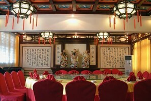 A conference room with red chairs, a table with a glass top, and traditional Chinese calligraphy on the walls.