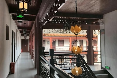A corridor with traditional architectural elements, a staircase with a railing, and hanging lanterns.. Nanyue Vegetarian Hall