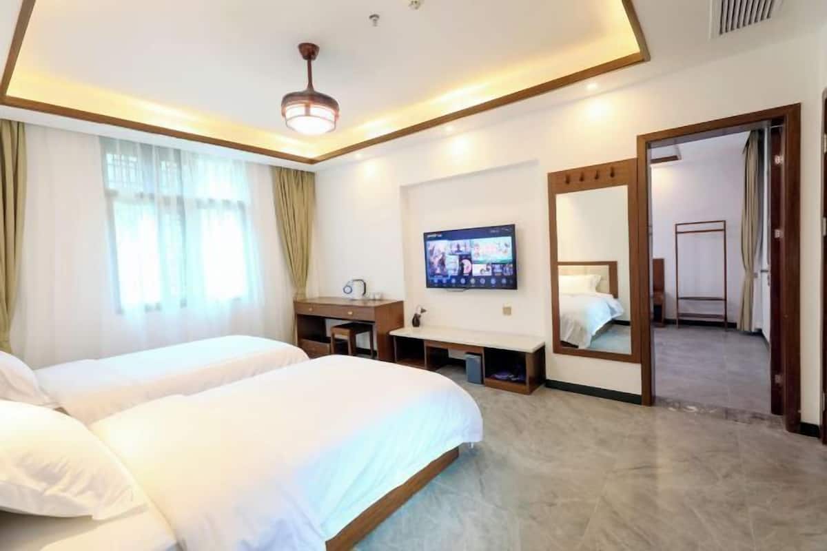 Une chambre d’hôtel avec deux lits, une télévision, un bureau et un miroir.