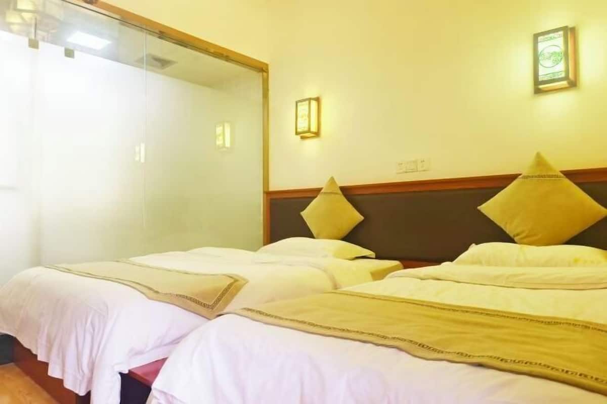 Une chambre d’hôtel avec deux lits, un grand miroir et un luminaire fixé au mur.