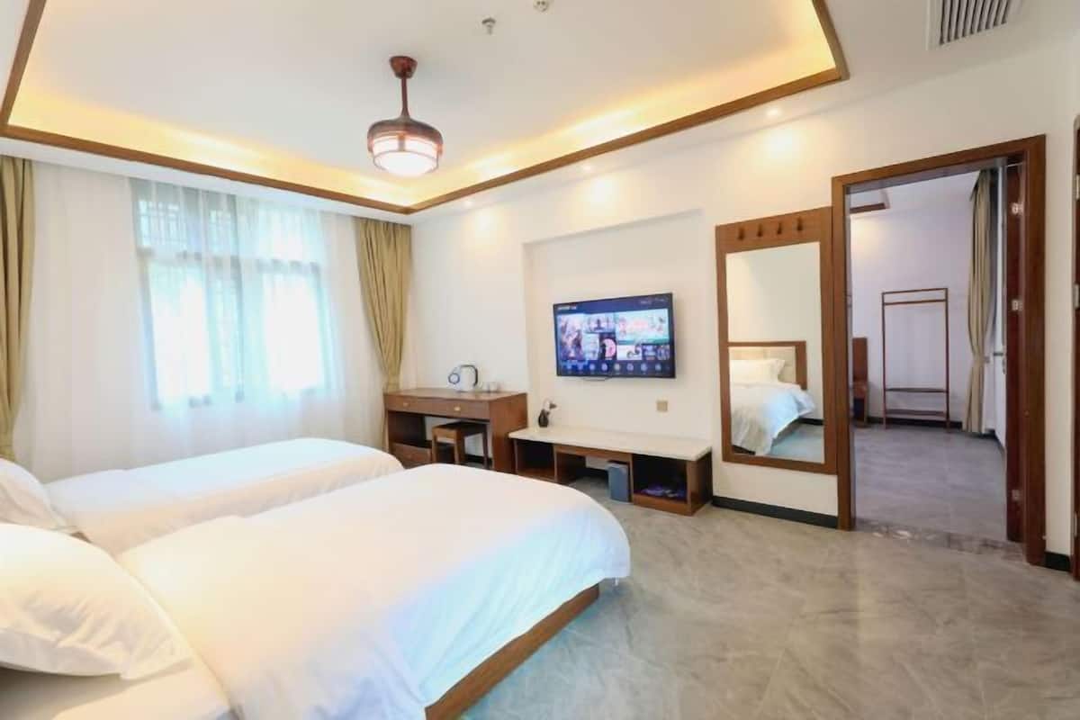 Une chambre d’hôtel avec deux lits, un bureau, une télévision et un miroir.