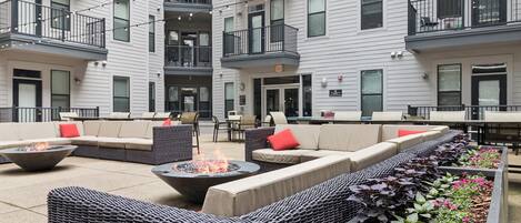 A courtyard with outdoor seating, fire pits, and a planter with flowers.