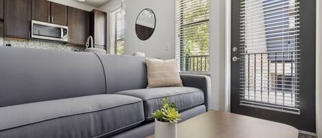 Una sala moderna con un sofá gris, una mesa de centro de madera y una planta en maceta.