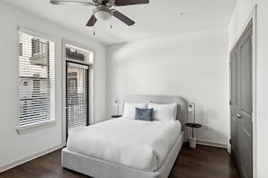 A bedroom with a bed, a ceiling fan, a nightstand, and a window with blinds. - Kasa At Artisan Music Row Nashville (Nashville)