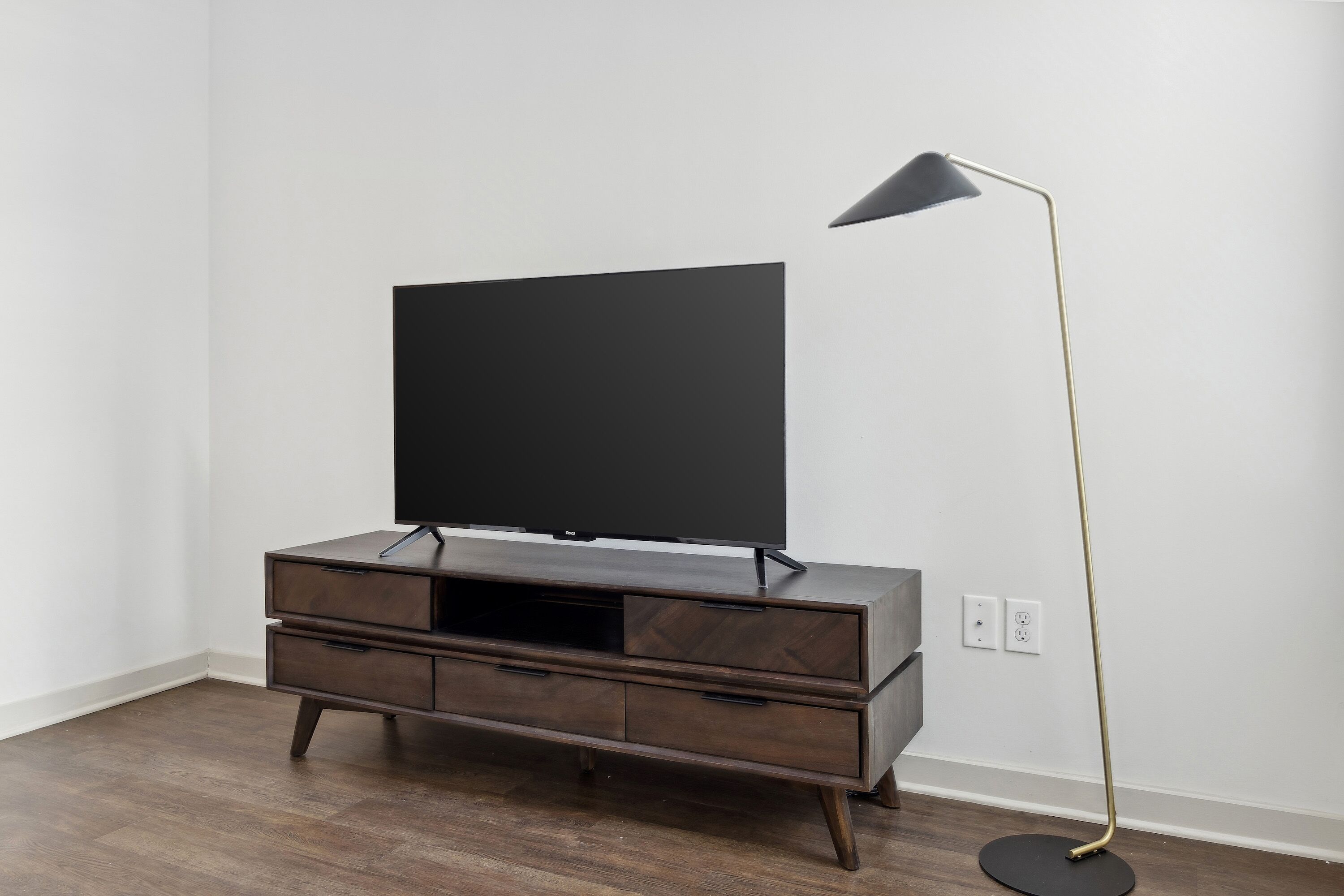 A modern entertainment center with a flat-screen TV and a floor lamp.