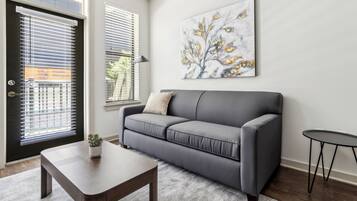 Uma sala de estar moderna com um sofá cinzento, uma mesinha e um quadro na parede.