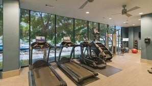 Un gimnasio con cintas de correr, elípticas y pelotas de ejercicio.