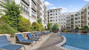 A swimming pool area with lounge chairs and a building with multiple balconies. - Kasa Village District Raleigh (Raleigh)