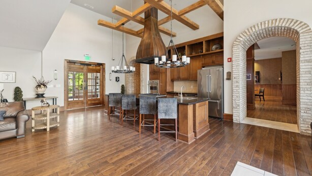 A spacious kitchen with a central island, wooden beams, and a brick archway leading to another room. - Kasa Village District Raleigh (Raleigh)