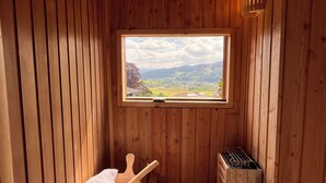 A wooden sauna room with a bench, a towel, and a heater. - Graceland in the Black Forest (Fischerbach)