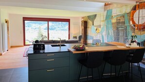 A modern kitchen with a large island, a dining area with bar stools, and a view of the outdoors. - Graceland in the Black Forest (Fischerbach)
