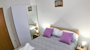 A neatly made bed with a patterned bedspread, two pillows, and two rolled towels. - Apartment Tina (Ražanac)