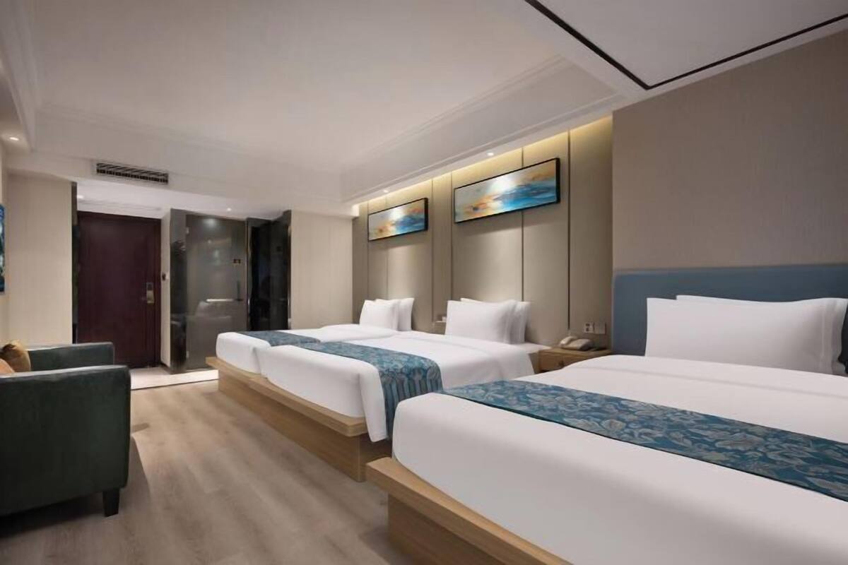 A hotel room with two beds, a sofa, and a painting on the wall.